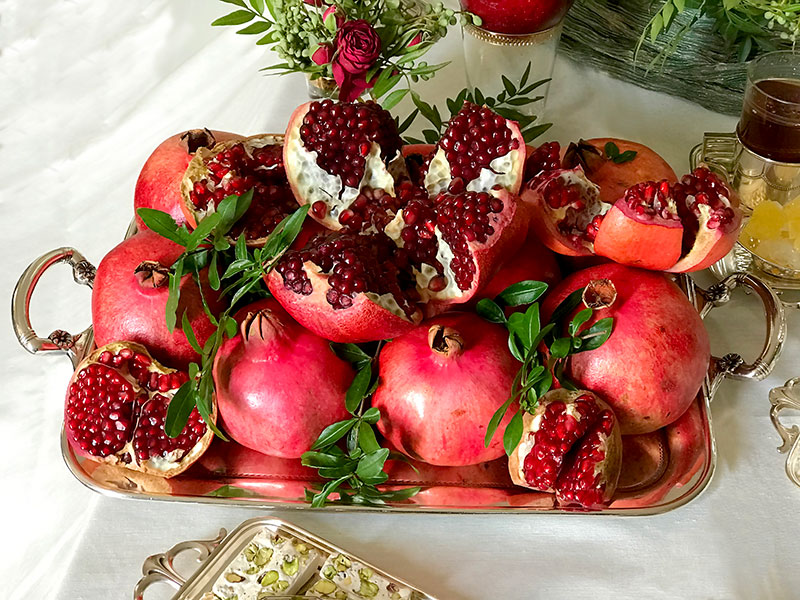 whole and opened pomegranates and sprigs