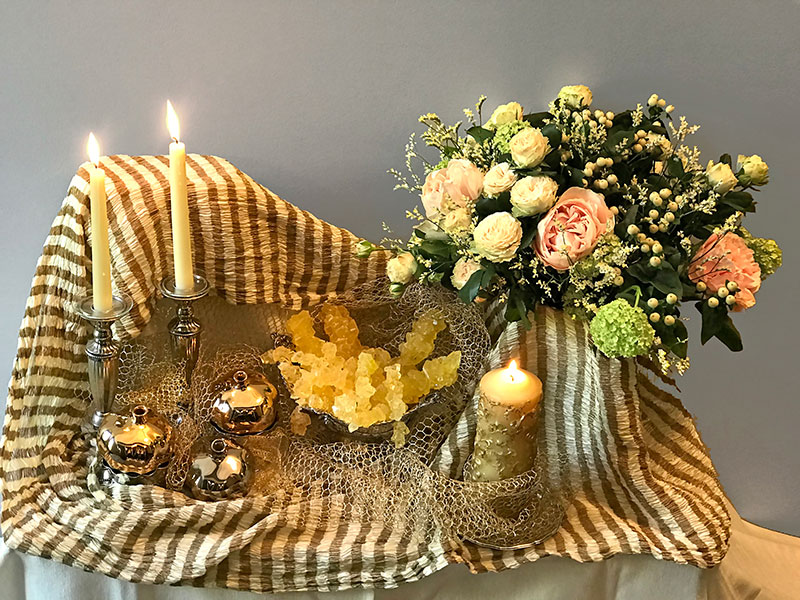 indian textile, candles, crystal sugar, and bouquet