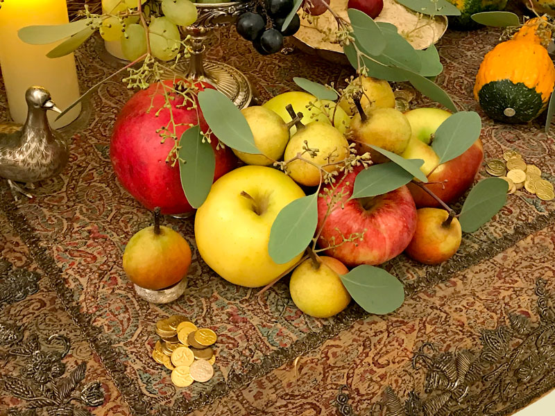 Sofreh decorated with a variety of seasonal fruit, namely apples, miniature pears and a single pomegranate.