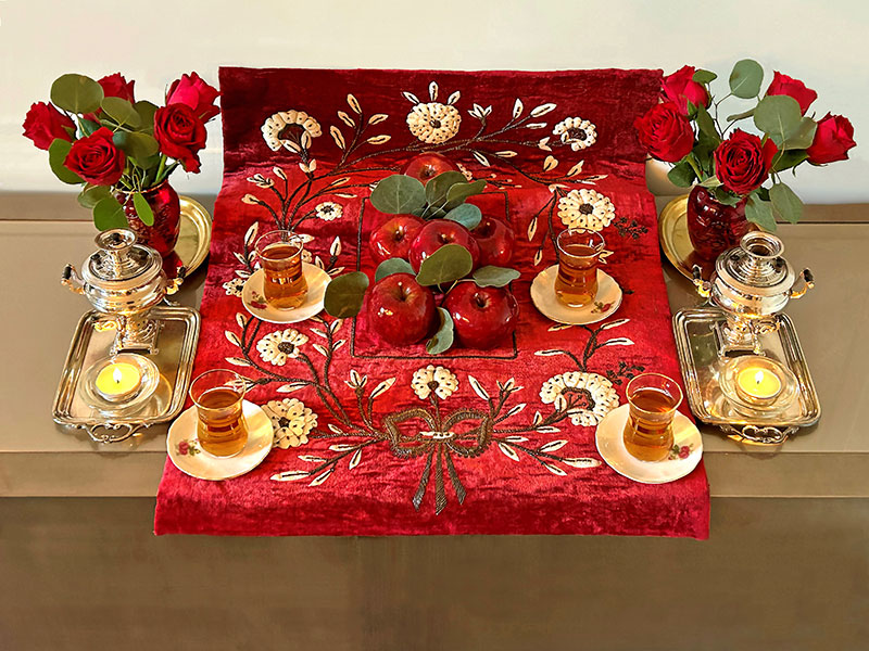 Tea, apples, tea lights and roses on red cloth