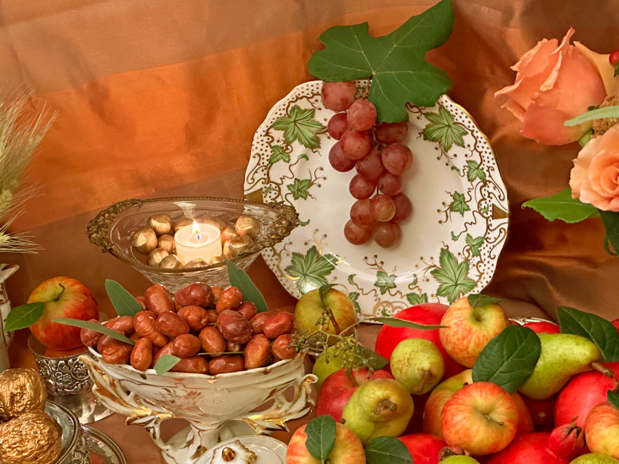 red grapes and a single vine leaf hang on an antique porcelain plate